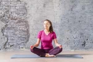young-woman-meditating-lotus-pose-against-damaged-grey-wall-1.jpg