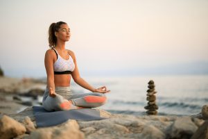 young-woman-practicing-yoga-relaxation-exercises-meditating-rock-beach-copy-space.jpg